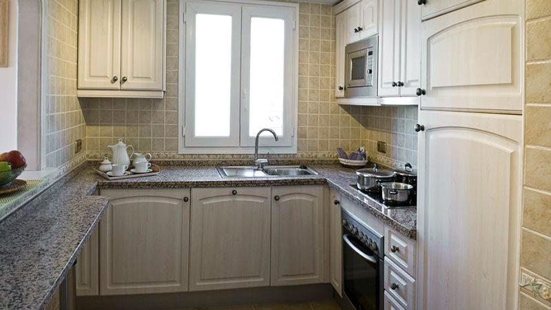 Kjøkken med vask, stekeovn, kjøleskap med fryser og kjøkkenbenk. Mye skapplass. 
